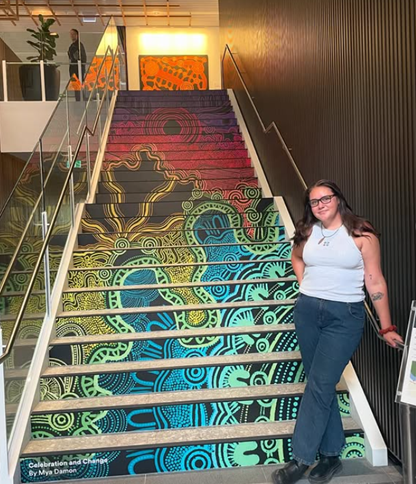 Photo of Mya Damon with her art installation Celebration and Change shown on the stair risers